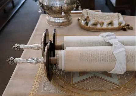 A table with two torah scrolls and silver serving dishes.